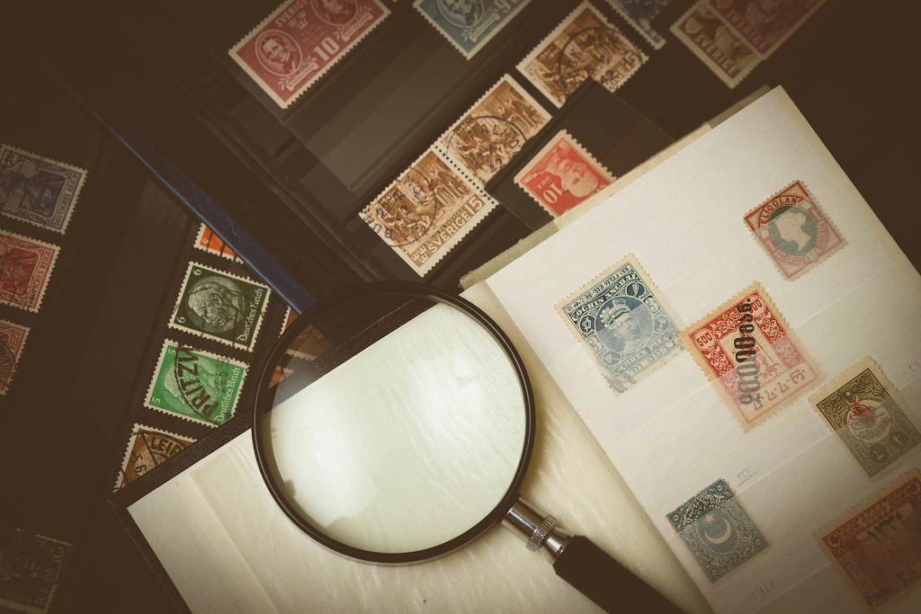 Explore a detailed view of vintage postage stamps through a magnifying glass, highlighting intricate designs.